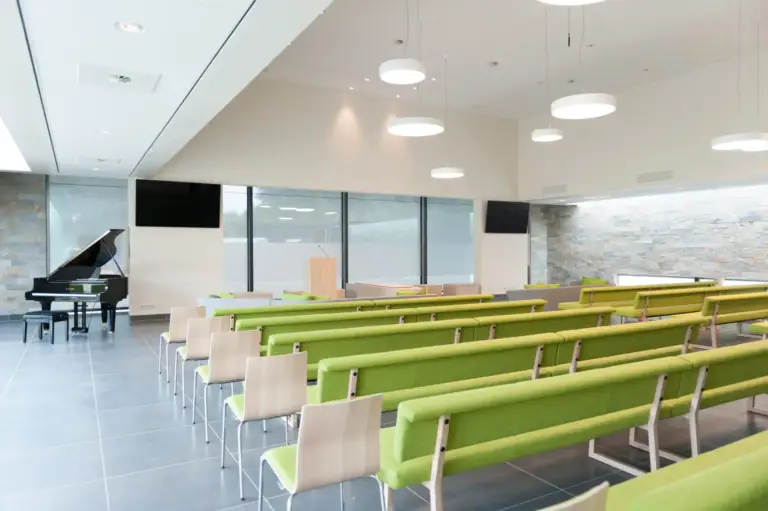 Aula Polderzicht in Crematorium Heerhugowaard, met groene banken en een vleugel